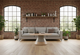 Byorne Coffee Large Table by Quell Design featured in a modern living room with exposed brick walls, wooden flooring, high ceilings, large windows, and lush greenery. The table showcases a rounded oval wood veneer top and bold single pedestal base, combining natural warmth with minimalist Scandinavian design. Crafted from eco-friendly materials, it serves as an elegant focal point that brings balance and sophistication to contemporary interiors.