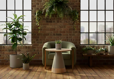 Byorne Side Table by Quell Design placed in a bright contemporary room with exposed brick walls, oak floors, large windows, and lush greenery. Featuring a soft oval white oak top and mocha-toned rounded base, this sculptural side table blends natural warmth with minimalist Scandinavian design. Crafted from eco-friendly materials, it brings refined simplicity and balance to modern living and lounge spaces.